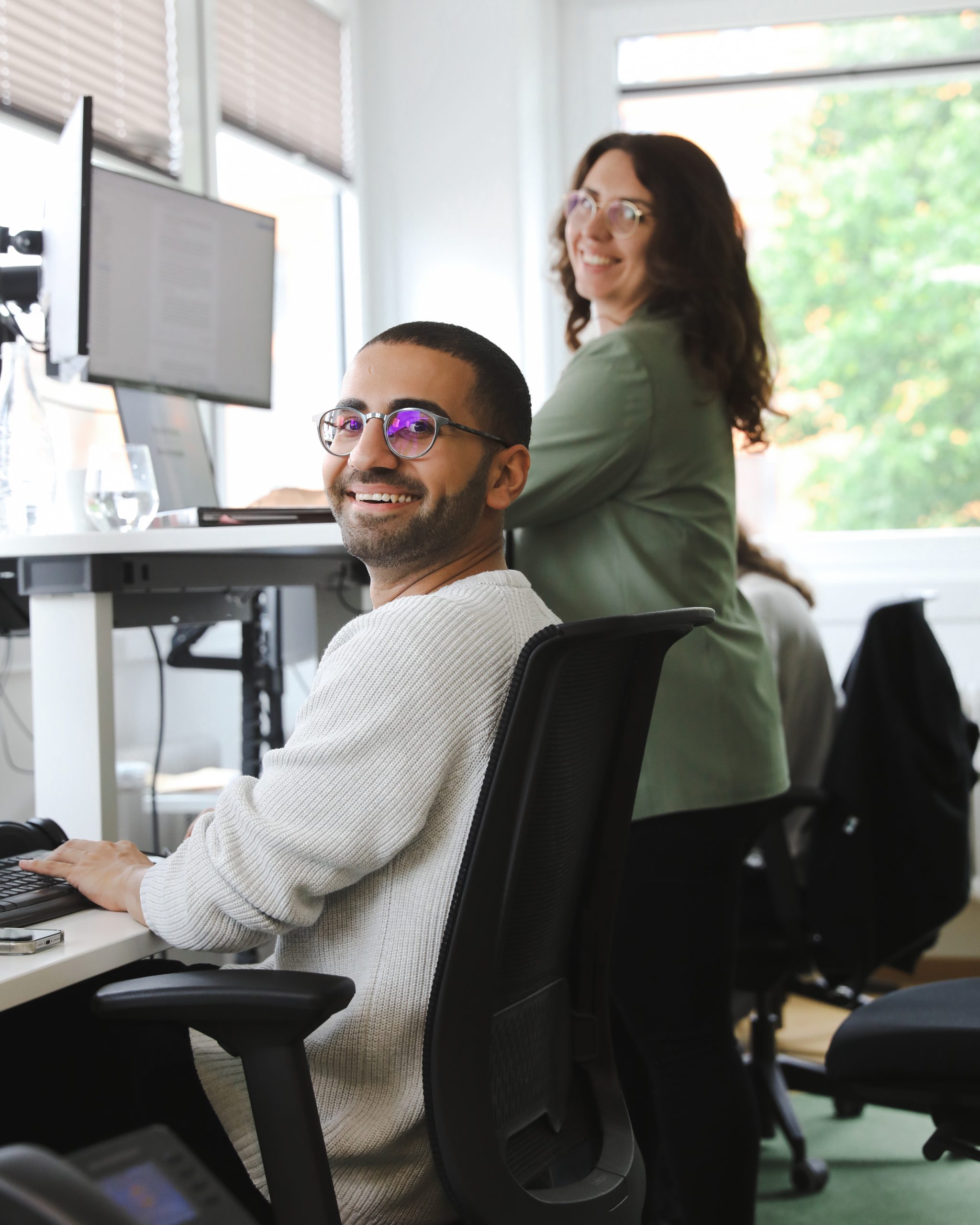 Ein Mann und eine Frau stehen nebeneinander und lachen in die Kamera