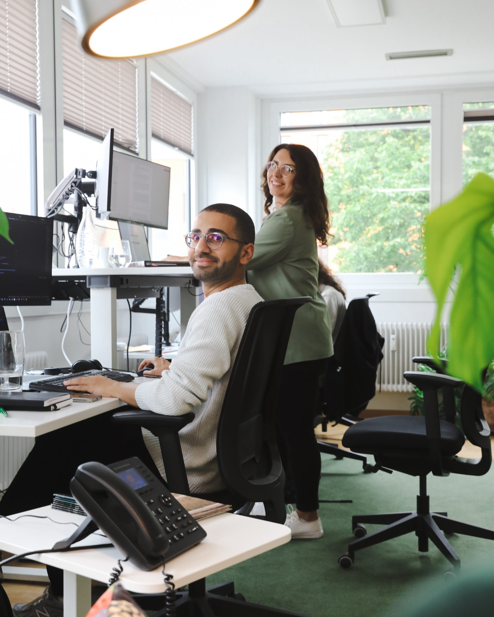 Zwei Personen sitzen vor dem PC in einem Büro, sie lachen in die Kamera Digitales Zertifikat