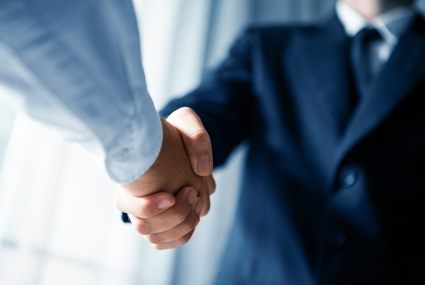 Zwei Männer in Business Kleidung schütteln sich die Hände Vertrauensdienste